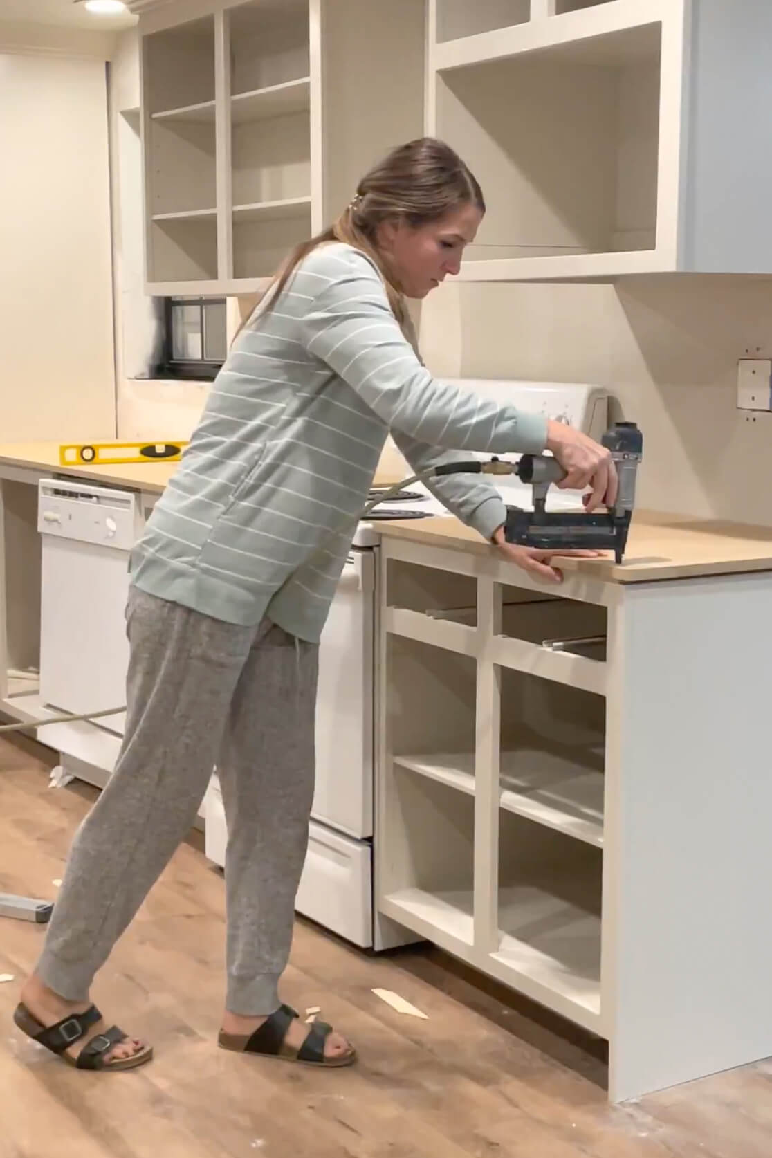 Using a brad nailer to attach a countertop to the cabinet boxes.